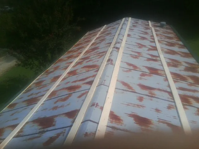 Rusted metal roof panels with new wood purlins before replacement — Storm Damage Roof Repair in Delano by Roofing Brothers